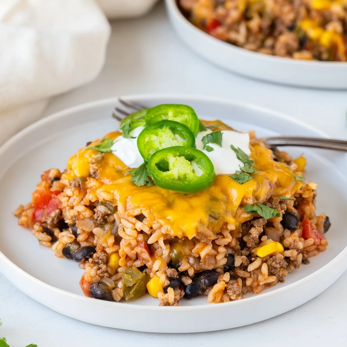 Savory Tex-Mex Beef & Rice Casserole ready to serve with sour cream and jalapeños.  