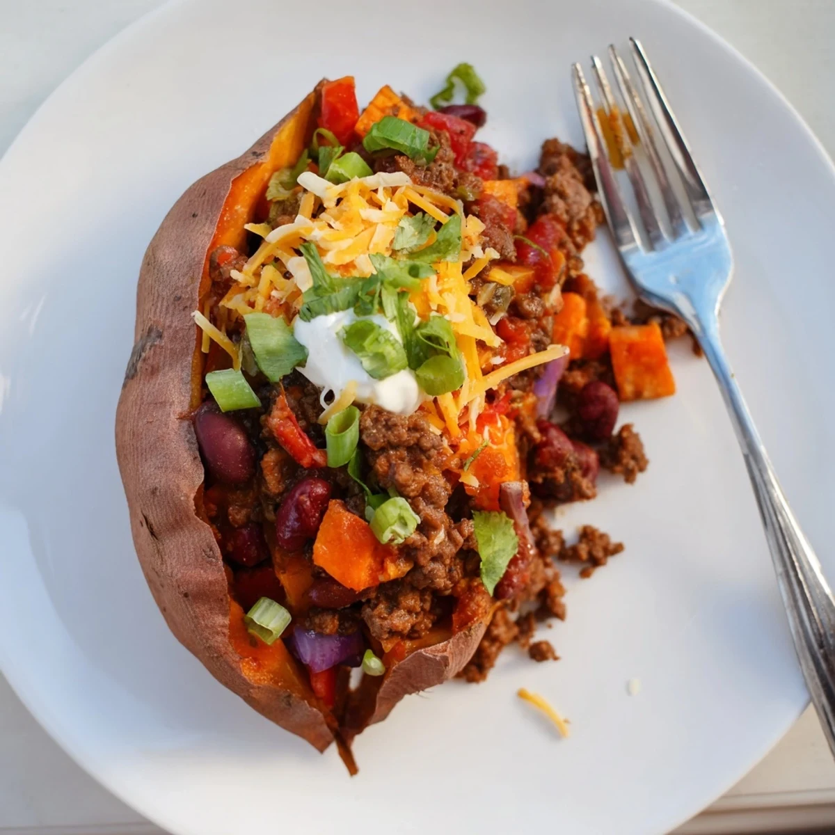 Warm, fluffy Baked Sweet Potato Stuffed with Chili is topped with fresh green onions and cheese.