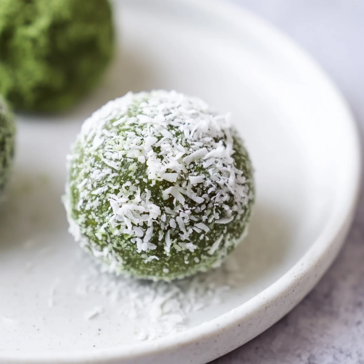 Close-up of creamy Coconut Matcha Snowball Fat Bombs, offering a delightful bite of coconut and matcha.