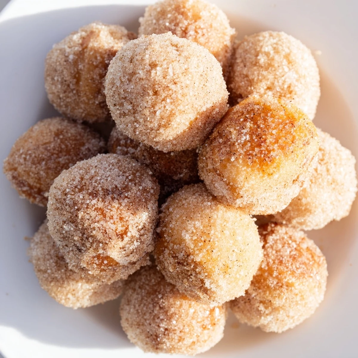 Fluffy, golden Air Fryer Cinnamon Donuts sprinkled generously with a warm cinnamon-sugar coating.
