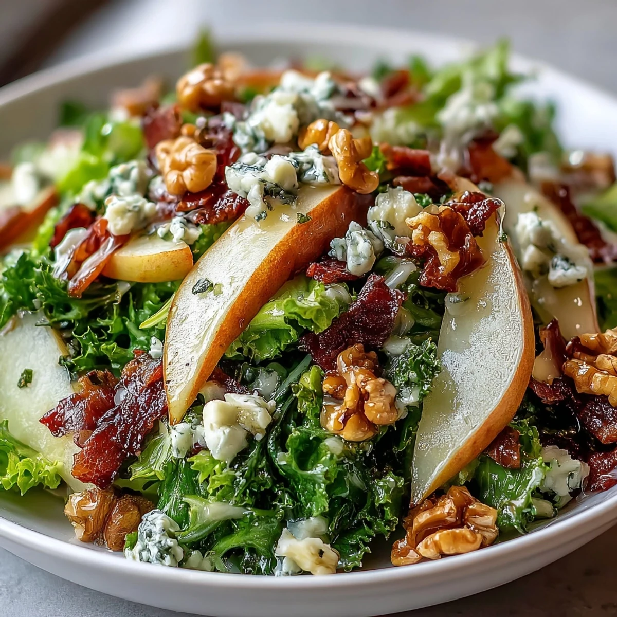 A vibrant Frisée Pear Blue Cheese Bowl tossed in vinaigrette, featuring walnuts, pears, and crisp prosciutto.
