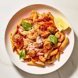 Close-up of a bowl of One-Pot Diavola Pasta with shrimp, garnished with fresh basil and Parmesan.
