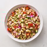 This hearty dense bean salad with prosciutto shows tender beans, veggies, and flavorful dressing ready.