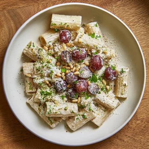 Pasta with Roasted Grapes and ricotta, displaying glistening grapes and herbs atop creamy pasta.