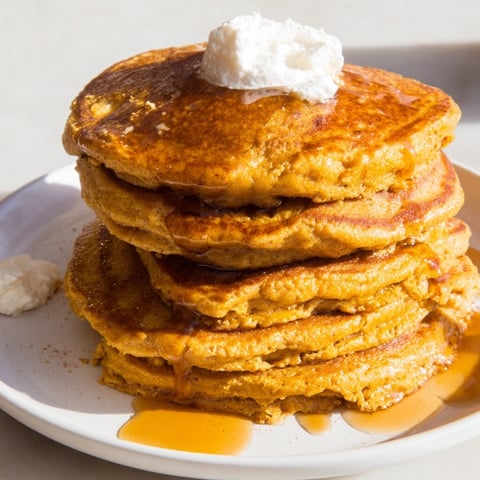 Fluffy pumpkin spice pancakes, golden brown and stacked high, ready to be drizzled with syrup.