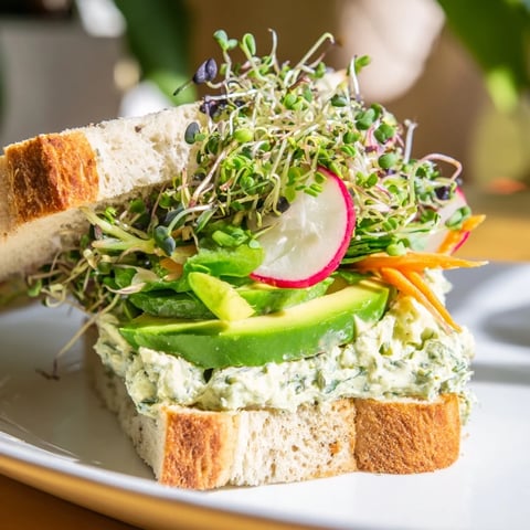 Creamy Green Goddess Sandwiches, bursting with vibrant veggies, served on toasted sourdough bread for lunch.