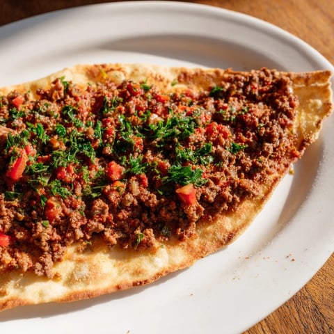 Crispy homemade Turkish Lahmacun flatbread topped with savory spiced meat, ready to eat.