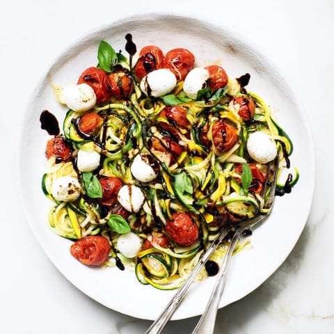 Caprese Zoodle Skillet sizzling: Soft zucchini noodles, melted mozzarella, and fragrant basil aroma.