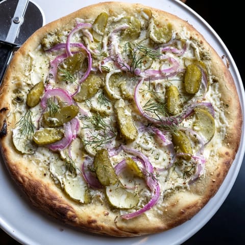 Deliciously unique Pickle Pizza featuring crème fraîche and fresh dill accents.  
