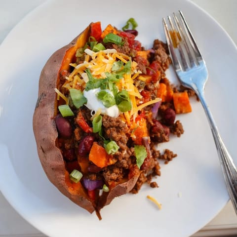 Warm, fluffy Baked Sweet Potato Stuffed with Chili is topped with fresh green onions and cheese.