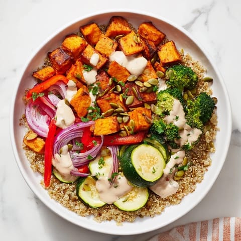 A colorful Quinoa Bowl showcases caramelized roasted vegetables atop fluffy quinoa, ready to eat alongside a zesty dressing.