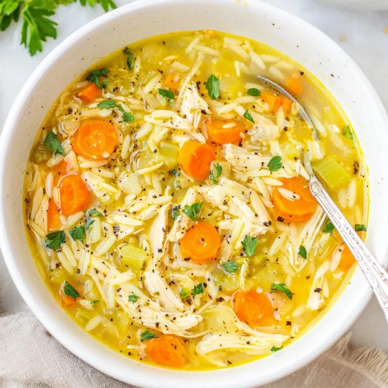 Tender shredded chicken and orzo pasta swim in a bright, savory broth infused with zesty lemon and black pepper.