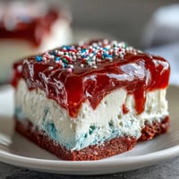 Festive Patriotic Poke Cake with vibrant gelatin filling and creamy white chocolate ganache.